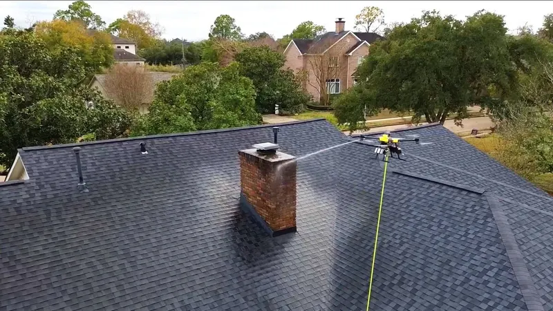 Drone soft-washing a shingle roof